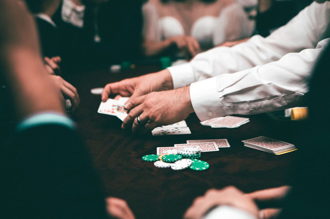 Pemain poker memegang kartu di atas meja penuh chip